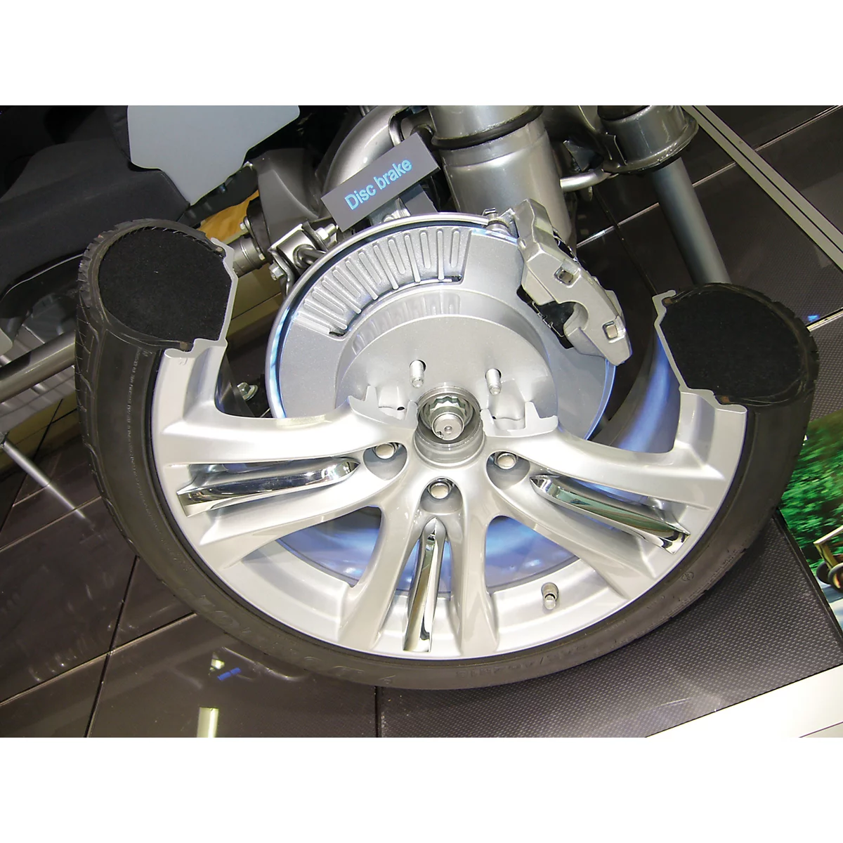 Vue en coupe d'une roue de voiture, montrant le disque de frein, l'étrier et le pneu.